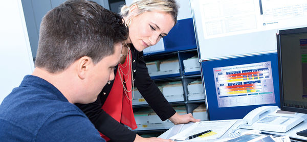 Two people look at documents at a desk